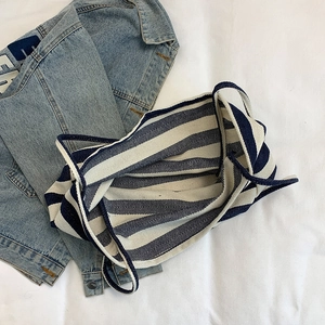 Large blue and white striped canvas tote bag with woven handles on white fabric