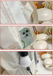 Detail of hidden zipper pocket, reinforced stitching and drawstring side pouch on white backpack