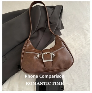 Detail of vintage brown dumpling bag featuring a large silver buckle and side zippers