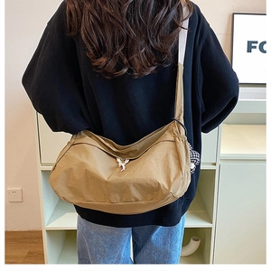 Détail du sac hobo en nylon kaki avec bandoulière rayée porté par le mannequin