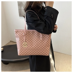 Close-up of pink monogram tote bag with gold M-logo pendant and premium texture