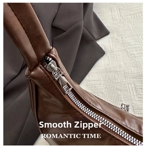 Detail view of smooth silver metal zipper on premium dark brown leather crescent bag