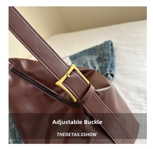 Macro detail of brown leather tote with vintage adjustable metal buckle and stitching