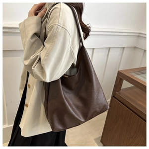 Close-up of brown textured leather tote bag worn on shoulder for minimalist daily fashion