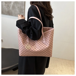 Pink tote bag detail with letter pattern print and gold logo charm on slim shoulder strap