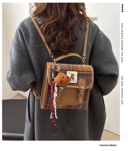 Detailed back view of a mini brown plaid tweed backpack with leather straps on a model
