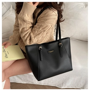 Detailed view of black leather tote bag worn with beige sweater in lifestyle setting