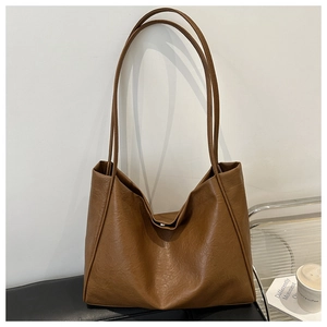 Détail d'un sac cabas en cuir marron foncé avec texture grainée et fermoir magnétique