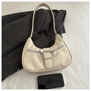 Detail of beige crescent shoulder bag featuring silver buckle and zipper accents