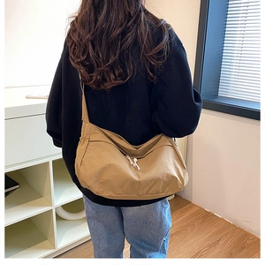 Détail de la bandoulière réglable et du tissu en nylon kaki foncé d'un sac demi-lune