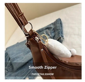 Detail of smooth zipper closure on brown PU leather tote bag with plush heart charm