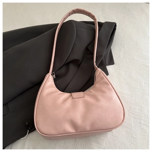 Detail view of pink faux leather half-moon shoulder bag on white textured surface