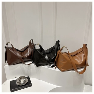 Three minimalist leather crossbody bags in dark brown, black, and tan on a white display