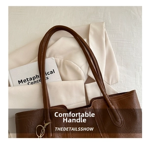 Detail of brown litchi pattern leather tote bag with long handles and stitching accents