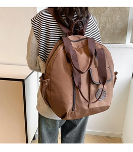 Brown nylon large capacity travel backpack shown on a model in a minimalist setting