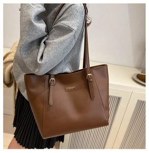 Detail of deep brown leather tote bag with adjustable strap and embossed fashion logo