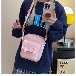 Gros plan sur un sac bandoulière en toile rose avec sangle réglable et boucles