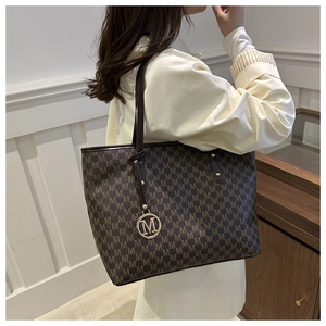 Detail of a brown monogram tote bag featuring leather shoulder straps and metal charm