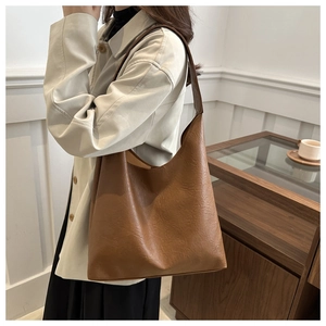 Detail of a large brown vintage faux leather tote bag with wide shoulder strap on a model
