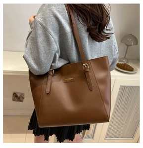 Macro shot of brown leather tote bag with gold buckle and embossed fashion label