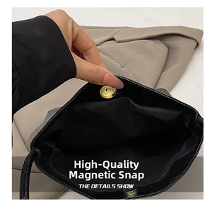 Detail of golden magnetic clasp on black crocodile pattern bucket bag with fabric lining