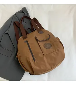 Detail of a brown large capacity backpack showing waterproof fabric and vertical zipper pockets