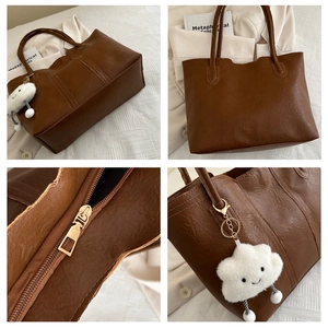 Macro details of brown faux leather tote with plush cloud charm and gold zipper