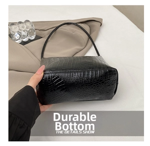 Detail showing high-quality black crocodile texture and durable reinforced bottom of the bag
