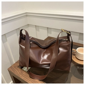 Detail of dark brown faux leather tote bag with smooth texture and golden metal buckle