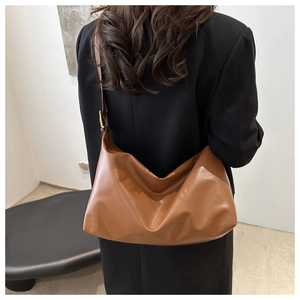 Close-up of caramel faux leather hobo shoulder bag shown on black blazer-clad model