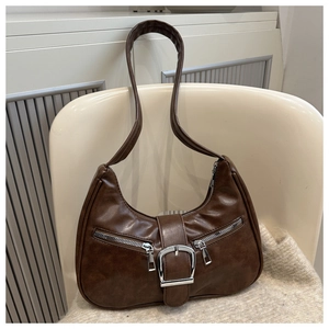 Detail of dark brown hobo bag with silver zippers and buckle on a neutral chair