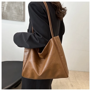 Grand sac cabas marron foncé en cuir texturé porté avec une veste de costume noire