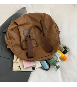 Brown large capacity tote bag displaying various travel items spilled from open main pouch