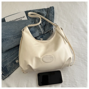Detail of cream leather shoulder bag with embossed fashion logo on a casual background