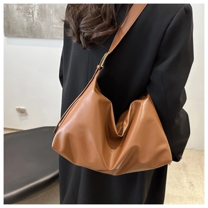 Detail of a brown leather hobo bag with adjustable strap and golden metallic buckle