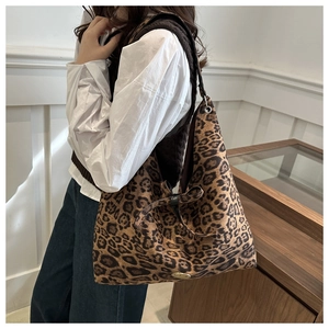 Detail of large leopard print tote bag featuring a decorative bow and handmade metal tag