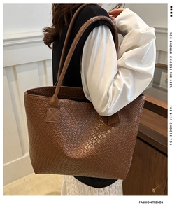 Macro detail of dark brown woven leather tote bag with elegant texture and long handles