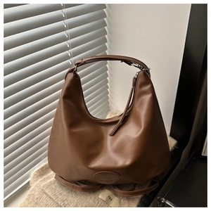 Detail of a brown leather hobo bag with embossed logo on a minimalist background
