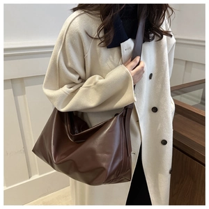 Detail of soft brown PU leather tote bag with stylish pleated texture and wide strap