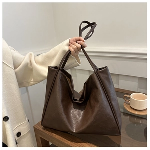Détail montrant la texture grainée du sac fourre-tout en cuir marron avec de longues anses