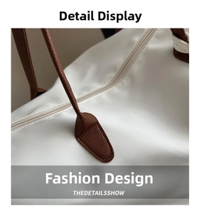 Macro detail of white nylon tote bag with brown leather handle and resin zipper