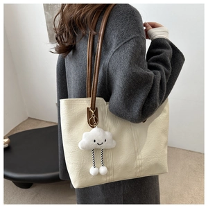 Dettaglio borsa tote in pelle crema con ciondolo a nuvola e tracolla marrone scuro
