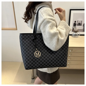 Detail of grey monogram tote bag with gold M pendant and knot shoulder strap detail