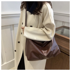 Deep brown large vintage leather tote bag shown on a model wearing a beige coat