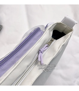 Close-up of the smooth zipper design and purple contrast fabric on the canvas messenger bag
