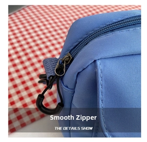 Detail of smooth black zipper and tight stitching on light blue nylon shoulder bag