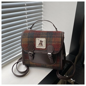 Close-up of retro plaid fabric texture and leather patchwork with bear embroidery on the bag