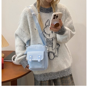 Détail d'un petit sac bandoulière en nylon bleu clair avec des boutons blancs et une sangle