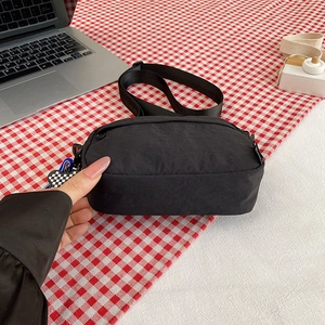 Waterproof black nylon crossbody bag with adjustable strap on a red checkered surface