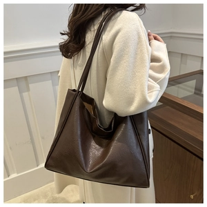 Vue détaillée du grand sac cabas marron en cuir porté par un mannequin en intérieur